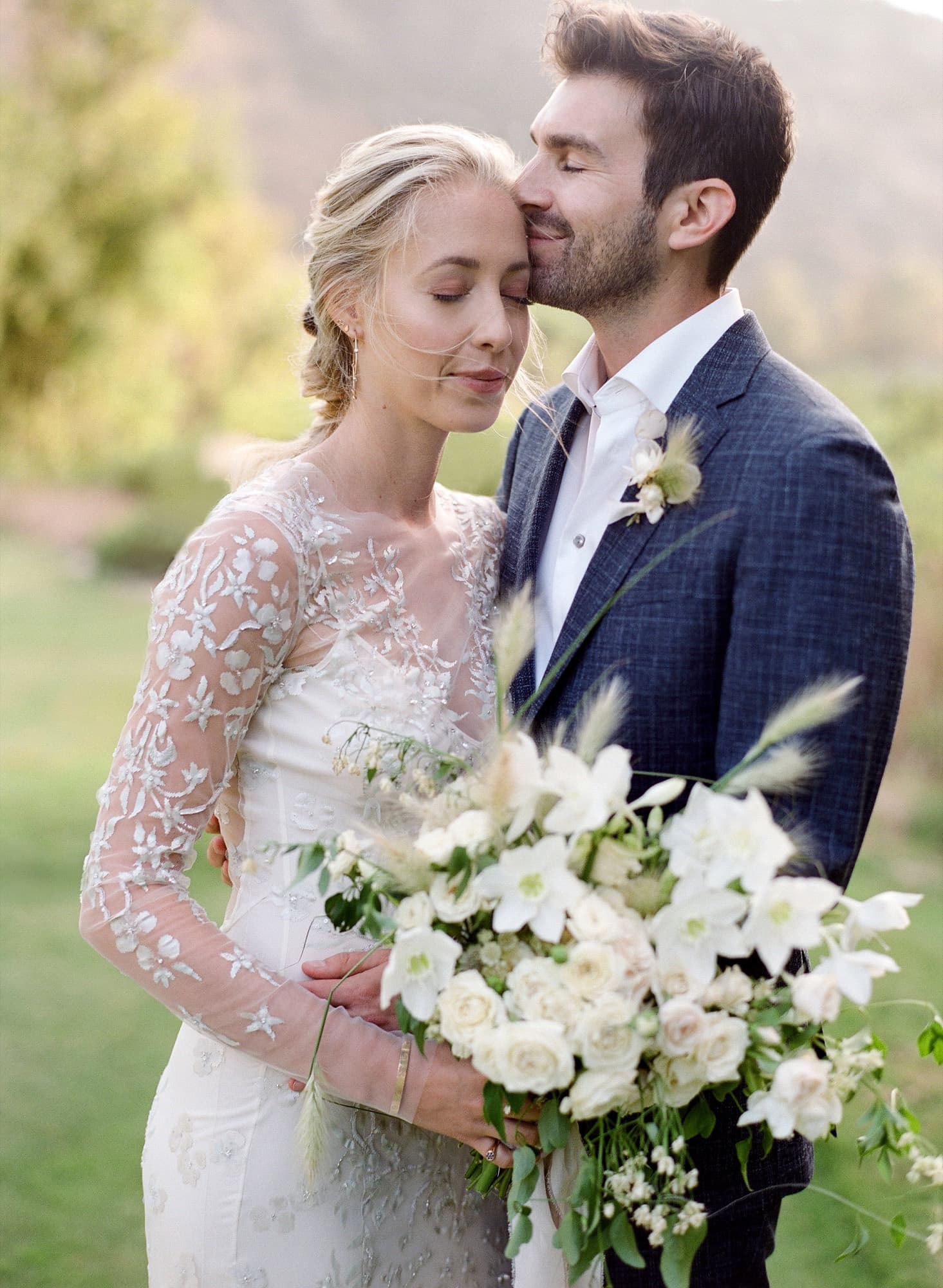 Bride and groom embracing with a bouquet of white flowers