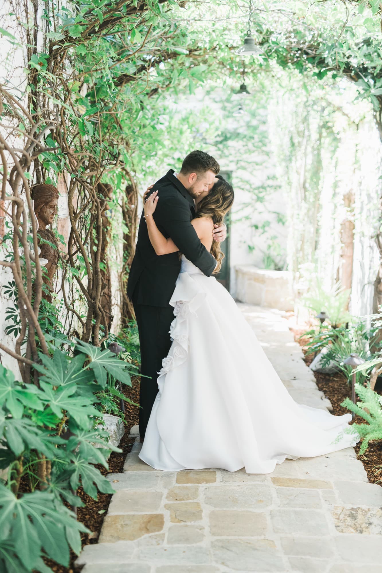 Bride and groom embracing under a vine-covered garden archway