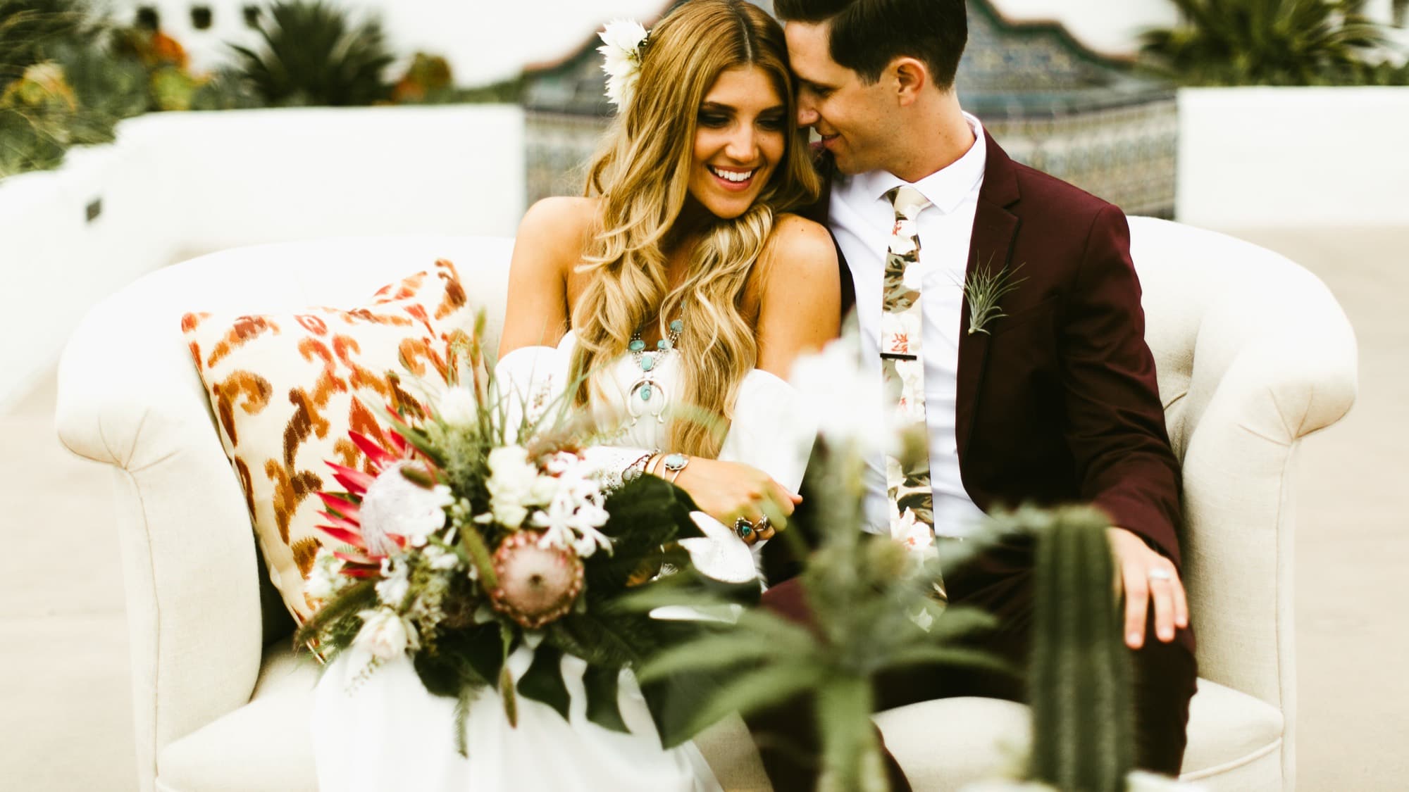 Newlyweds laughing together on a vintage loveseat